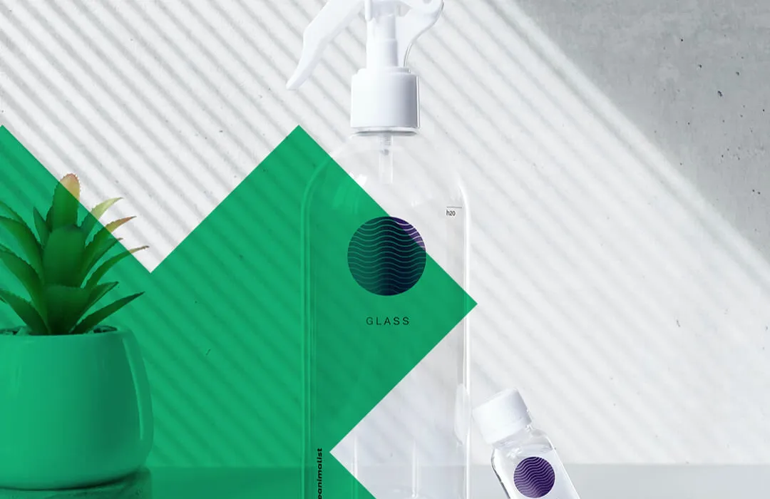 Sprühflasche aus Glas, im Hintergrund eine Grüne Pflanze
