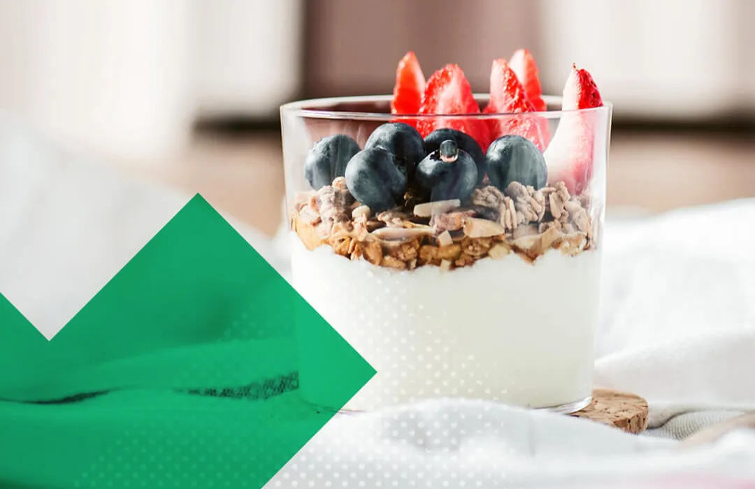 Glas mit Joghurt und Müsli und Heidelbeeren und Erdbeeren