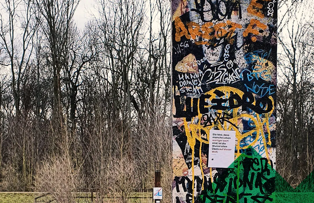 Die Idee, dass manche Leben weniger wert sind, ist die Wurzel allen Übels auf dieser Welt Aufkleber auf mit Graffiti bemalter Wand